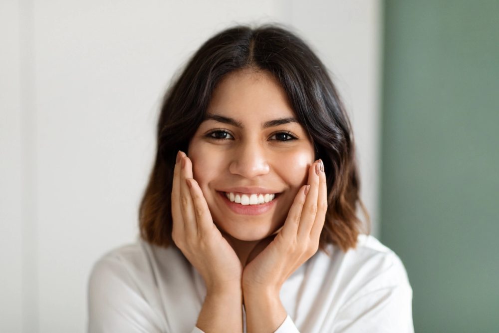 Smiling woman with her hands near her face